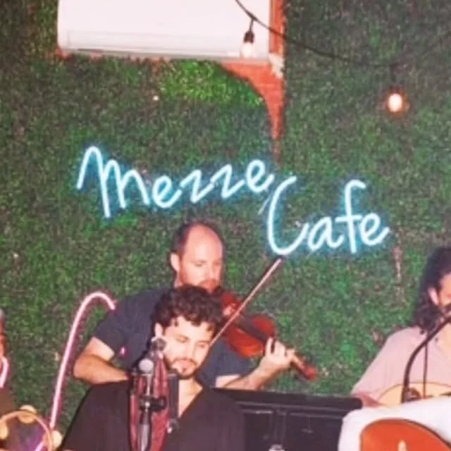 Live music night under the neon Mezze Cafe sign in Austin
