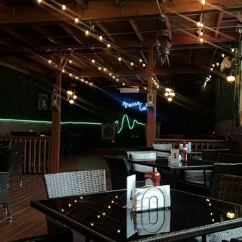String lights and the Mezze Cafe neon sign over patio tables at night