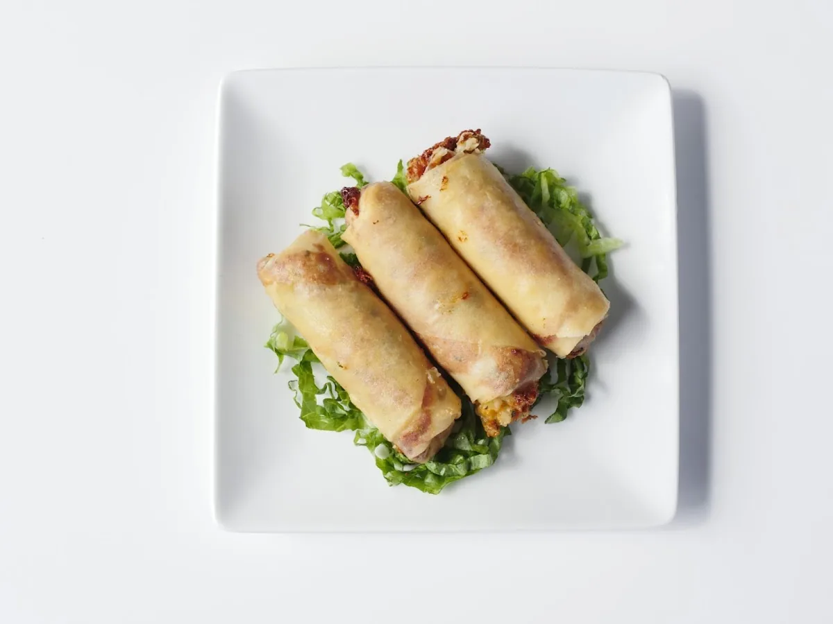 Crispy cheese rolls over shredded lettuce on a white plate, shot overhead