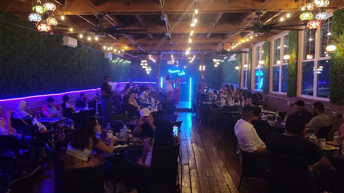 Groups of friends sharing hookah on the busy neon-lit patio at Mezze Cafe Austin
