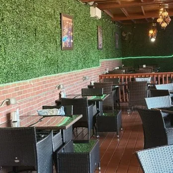 Wicker seating along the boxwood wall on the covered deck at Mezze Cafe Austin